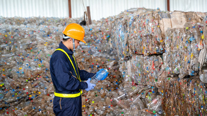 Engineer checking second hand plastic bottles In the background at waste recycling factory,Industry...