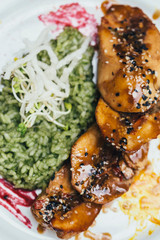 Chicken with risotto on a white plate from above close up
