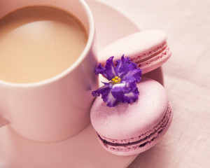 Two pink macaroons on the plate near cup with coffee