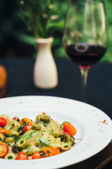 Pasta on a white plate with wine and flowers