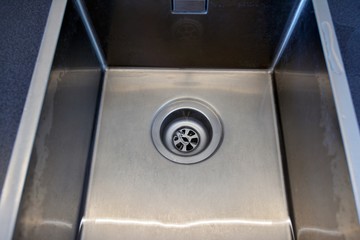 Stainless steel sink plug hole close up with water