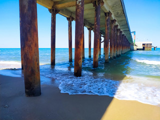 View under the dock at the beach. Coming and foamy waves under the dock