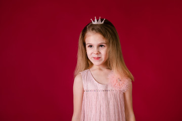 Beautiful little girl princess dancing in luxury pink and silver dress isolated on red background. Funny face, different emotions