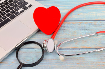 Conceptual image. Red heart, stethoscope, magnifying glass, thermometer, syringe and laptop on...