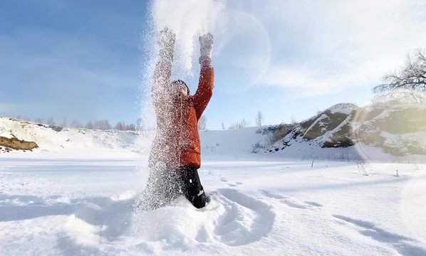 Boy is having fun with snow in a sunny winter day