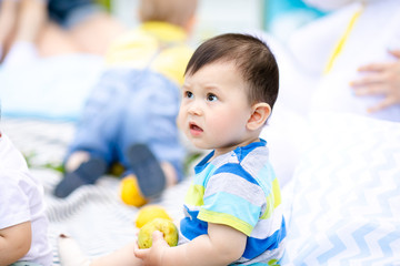 Cute little baby in summer park on the grass. Sweet baby outdoors. Smiling emotional kid on a walk