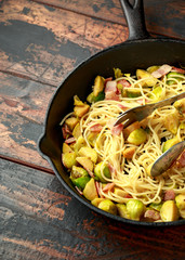 Homemade Brussels sprouts, bacon, pancetta pasta with parmesan cheese. On wooden table