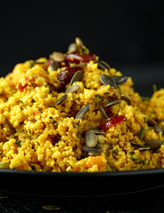 Morrocan style fruit couscous salad with raisins, dried apricots and pumpkin seeds on dark...