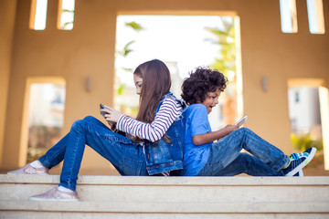 Two kids boy and girl playing with tablet outdoor. Children and gadget addiction concept