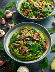 Vegan garlic mushroom pasta with spinach and avocado pesto drizzled with sesame seeds and roasted pine nuts