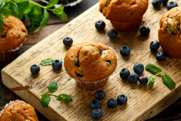 Blueberries muffins, cupcake with mint and berry on wooden board.
