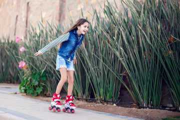 Smiling kid girl roller skate in the park. Children and activity concept