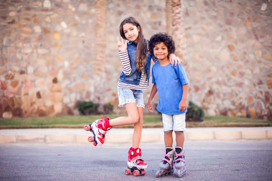Two happy kids boy and girl roller skate in the park. Children and activity concept