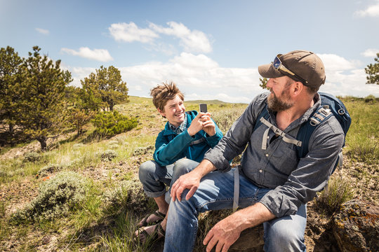 Father and son having fun taking pictures while hiking in rural prairie landscape. Cody, Wyoming, USA