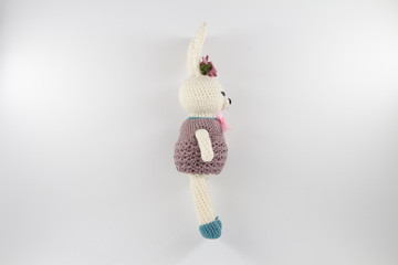 knitted toy rabbit in a sweater-dress with a flower on the ear on a white background