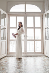 Portrait of elegant beautiful bride with unusual bouquet of flowers. Perfect makeup and hairstyle