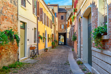 Fototapeta na wymiar Cozy narrow street in Ferrara, Emilia-Romagna, Italy. Ferrara is capital of the Province of Ferrara