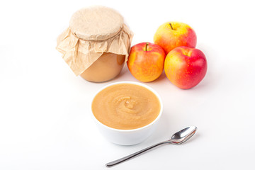 Fresh homemade applesauce in white bowl and jar with fruit puree on white table. The concept of proper nutrition and healthy eating. Organic and vegetarian food. Baby food. Copy space for text