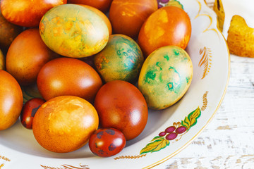 Easter eggs in a plate on an old white wooden background, retro style, rustic