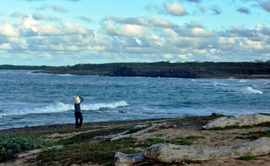 a fisherman walks along a wild beach on the Atlantic ocean coast. Dominican Republic