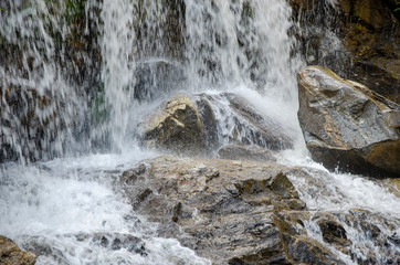 A stone with a flowing waterfall in the background with a blurred patterned background
