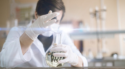 the student in white uniform with glass flasks doing research on the lesson in school