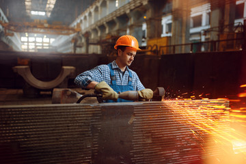 Worker in helmet works with metal workpieces