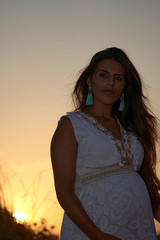 A young pretty pregnant woman on the beach at sunset
