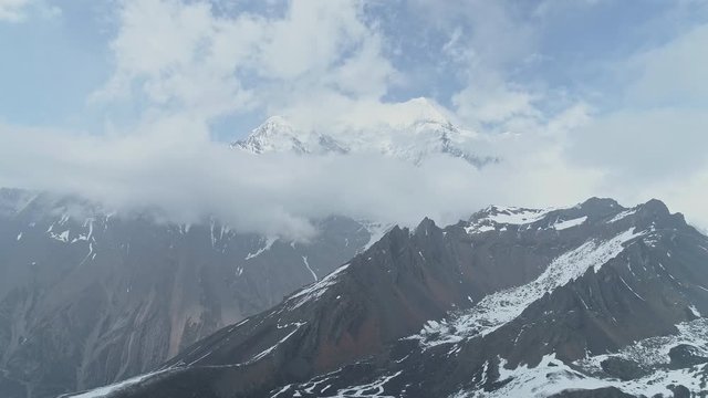 Fly near sharp snow rocks, sky-high Annapurna mountain towering in clouds,Nepal 