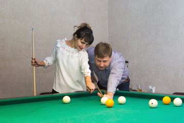 Man and woman play billiards. Adult man and a brunette woman stand near a table for a game of billiards.