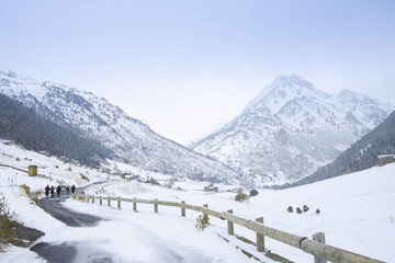 A group of people walking on an icy road in winter with the snow-capped mountains in the background...