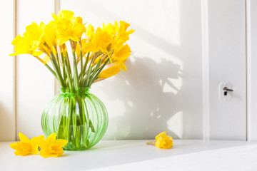 bright sunlight shines on Easter bells, daffodils flowers in vase on the windowsill. country style...