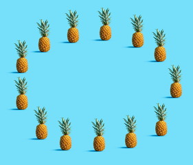 Fototapeta premium Round frame of pineapples on a solid color background