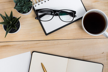 Workplace student. Business. Office. Diary, notebook, glasses, cup of coffee and plants on a wooden table.