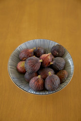 Ripe purple figs in dish on table