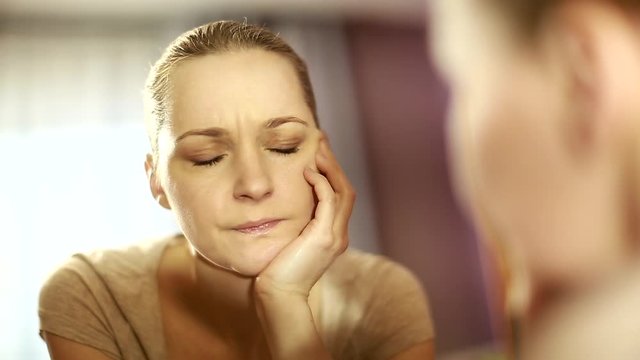 girl looks in the mirror, not pleased with the appearance, pulls the skin. Ugly, aging skin. Allergic to cosmetics, fear of aging, under eye circles, wrinkles. Low self-esteem, dysmorphic disorder. 