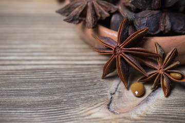 star anise with and without seed, closed, in a clay dish on a light wooden surface. spice for the recipe. beautiful picture, background