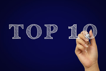 Female hand writing top ten text with white chalk pen in creative doodle style - Top 10 hand drawn copy with dark navy blue gradient background - Product awards, travel review and competition concept