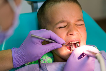 Dentists with a patient during a dental intervention to boy. Dentist Concept. At dentist's office