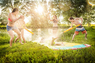 Group of young adults having fun in a swimming lake with a slip and slide. Bridger, Montana, USA