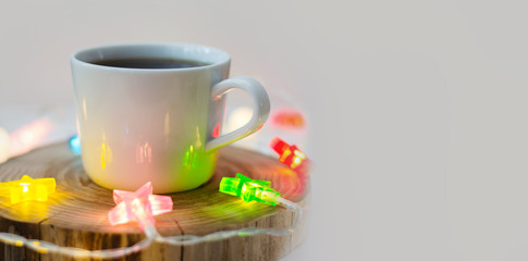 cozy still life with a cup of coffee on a wooden stand and colored garlands of stars