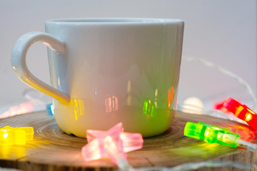 cozy still life with a cup of coffee on a wooden stand and colored garlands of stars