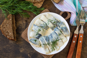 Mediterranean food. Seafood. Tasty appetizing pickled mackerel in a sauce with spices on a dark rustic wooden table. Top view flat lay background. Copy space.
