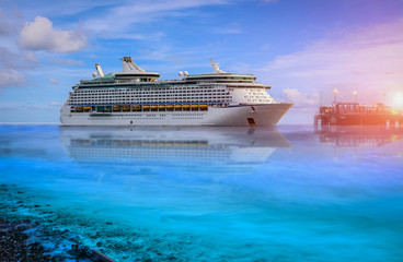 Cruise ship, large luxury white cruise ship liner on blue sea water and cloudy sky background.