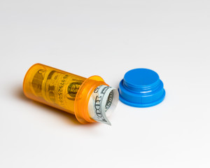 Prescription drug, medicine pill bottle with 100 dollar bill inside isolated on white background. Concept of rising drug, health care, medical insurance cost