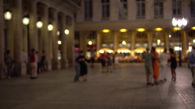Parisians and tourists dance elegantly in one of the squares of Paris. Bright shop Windows, beautiful building facade decorated with columns, in the background. Outdoor dancing, summer evening, Paris.