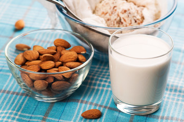 Almond milk in glass with almonds in bowl, on color wooden background