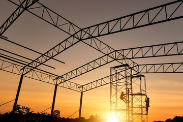 Construction worker wearing safety work at high uniform on scaffolding at construction site on during sunset,Working at height equipment.