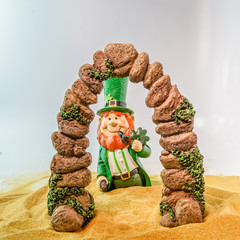 Leprechaun under and arch on a sandy beach on a white background.