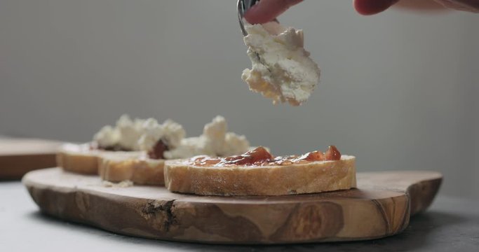 Slow motion man add ricotta to slice of ciabatta with fig marmalade and pancetta
